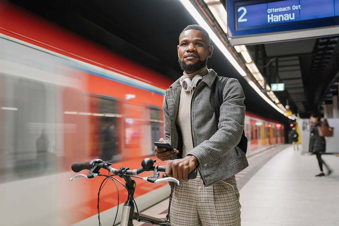 Man with bike on train platform as train goes past